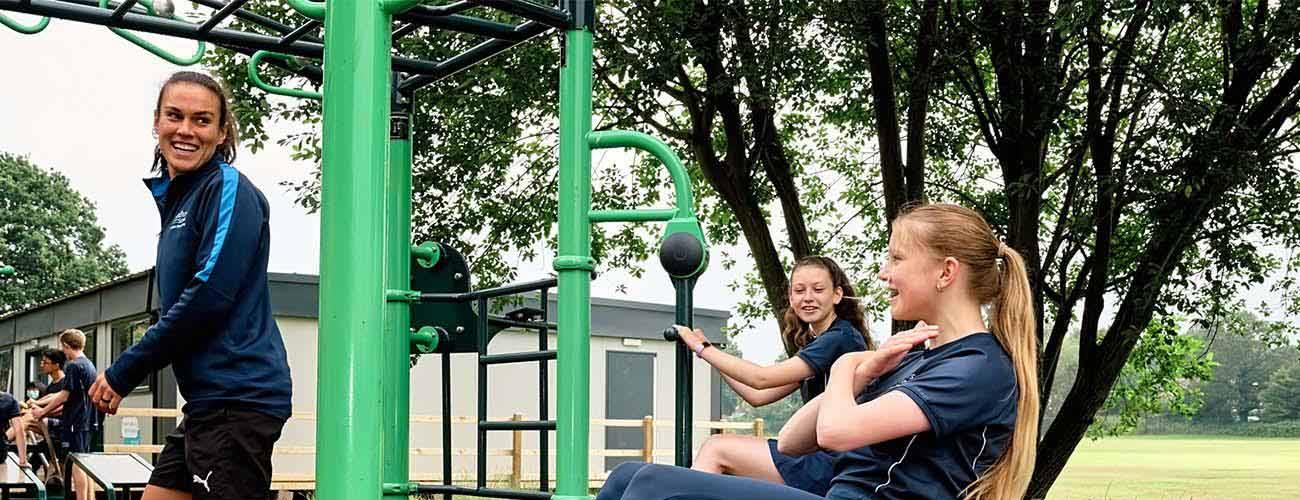 teacher and pupils using fresh air fitness big rig outdoor gym