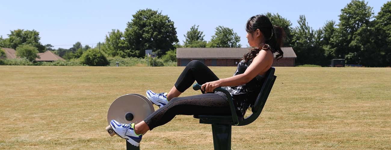 Lady using outdoor gym Recumbent Bike Fresh Air Fitness
