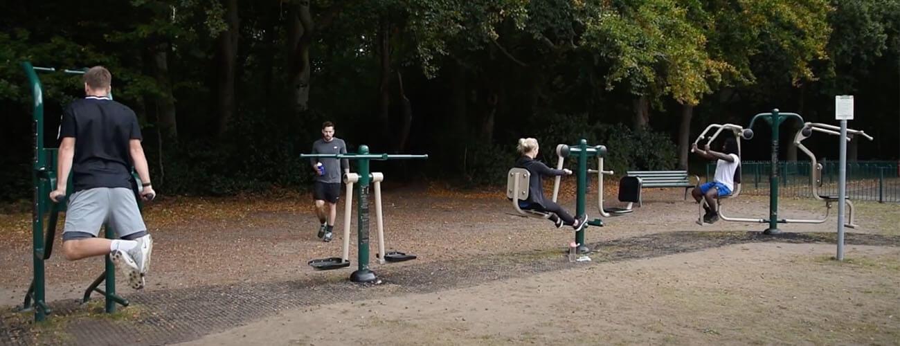 people using outdoor gym equipment in park 2m apart