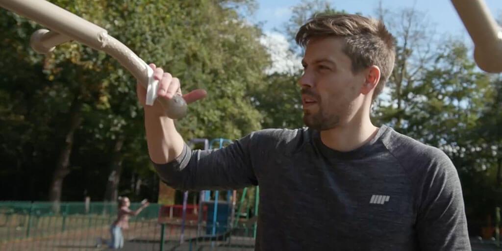 man cleaning outdoor gym equipment in park