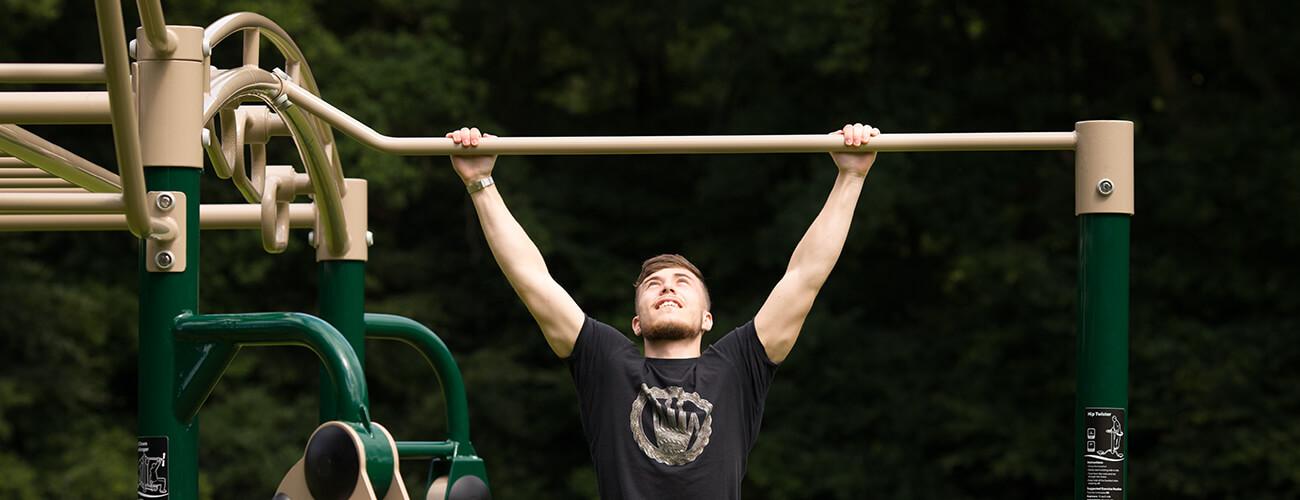 man performing pull ups on outdoor gym equipment 