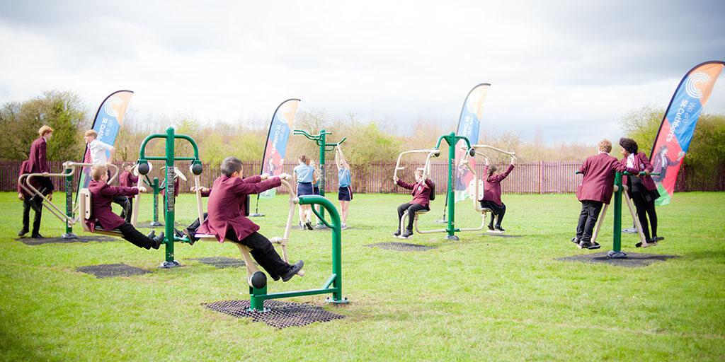 secondary school pupils using fresh air fitness outdoor gym at school