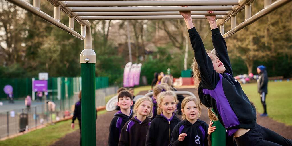 Children queueing to use the fresh air fitness monkey bars
