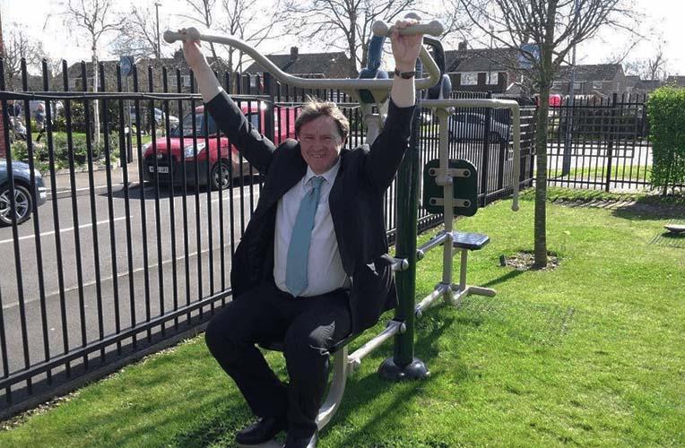 Man in suit on care home outdoor gym equipment