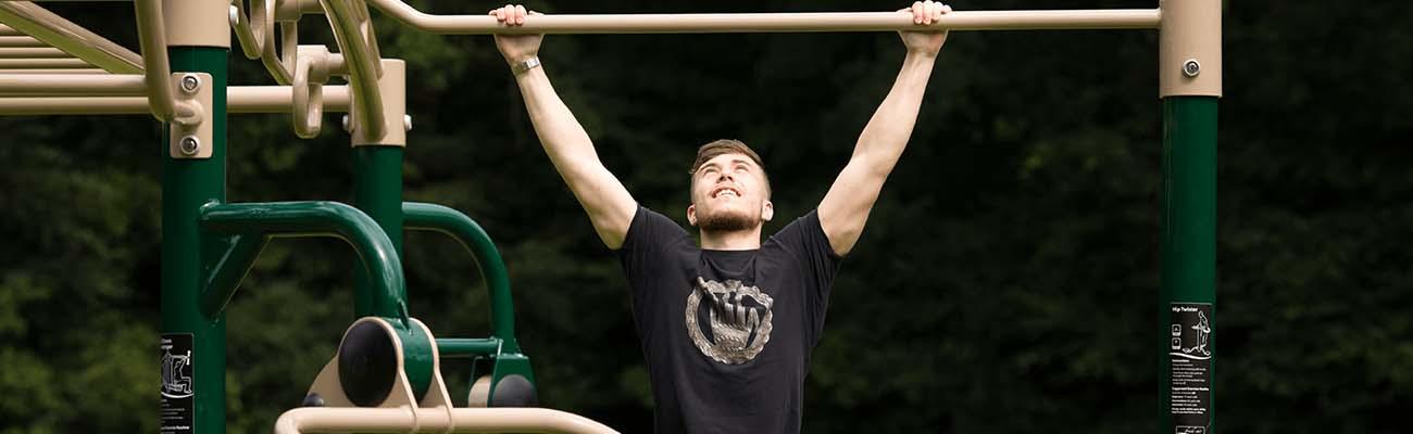 man performing pull ups in a park