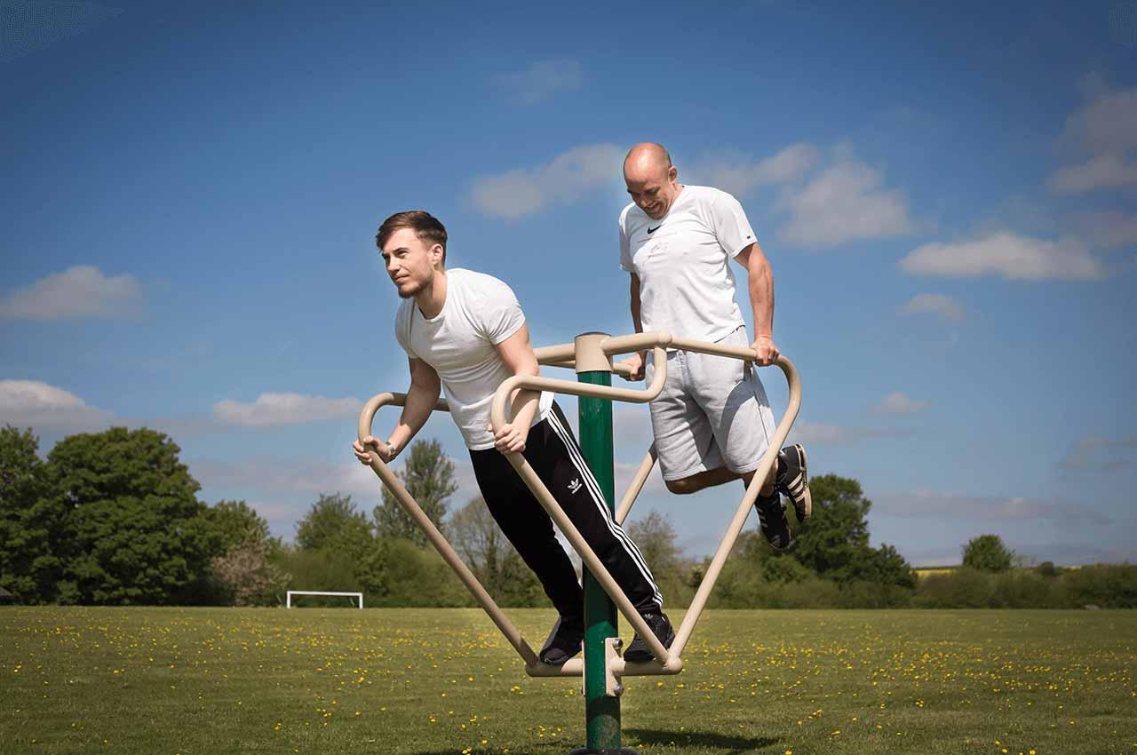 Two men exercising on a Fresh Air Fitness machine - and they don't care about outdoor gym equipment prices!